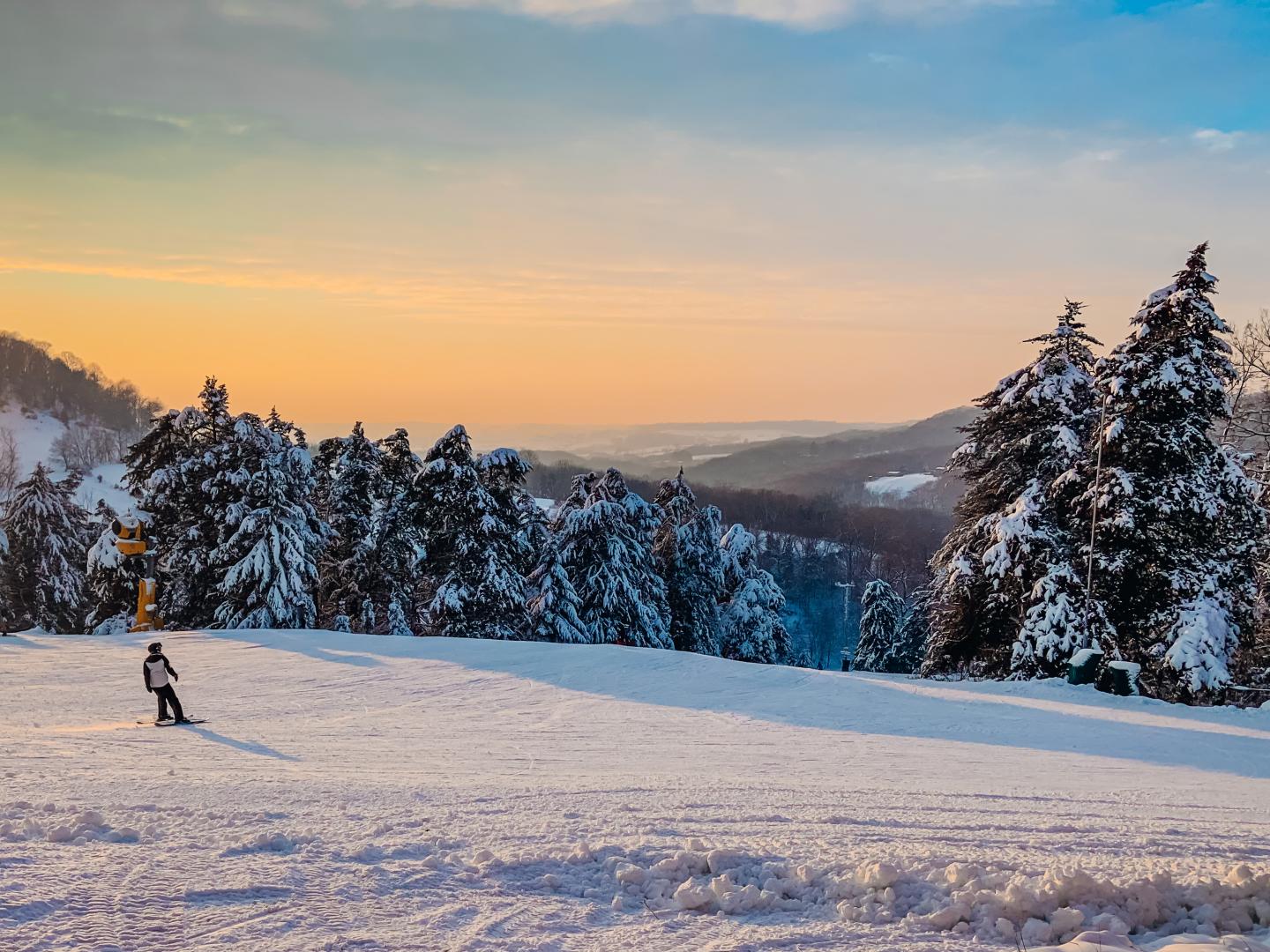 Sundown Mountain Resort in USA - a person on skis in the snow at sunset.