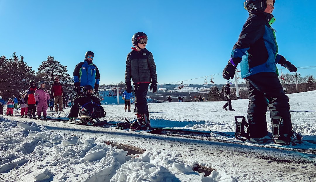 Winter sports scene at Sundown Mountain Resort in Dubuque, Iowa. Skiers, including a family, are enjoying the snow-covered slopes while others are riding the ski lift.