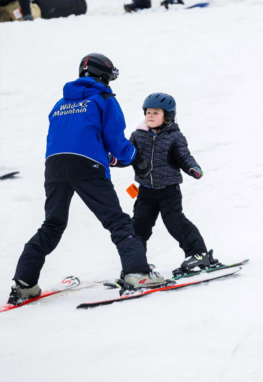 Wild Mountain in USA - a young boy skiing down a hill with an adult.