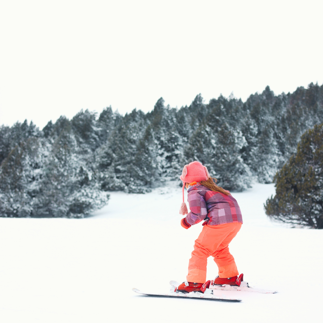 A skier and a snowboarder enjoying a sunny day at Les Angles winter sports centre in Pyrénées-Orientales, France. A child is also visible, learning how to ski.