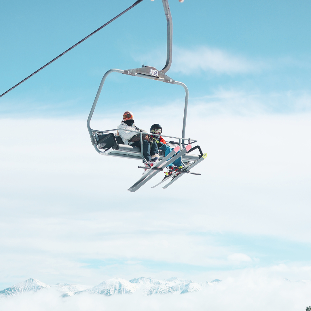 A skier is enjoying a winter's day at Les Angles ski resort in Pyrénées-Orientales France. The scene includes a ski lift and a charming chalet nestled amongst the snowy landscape.