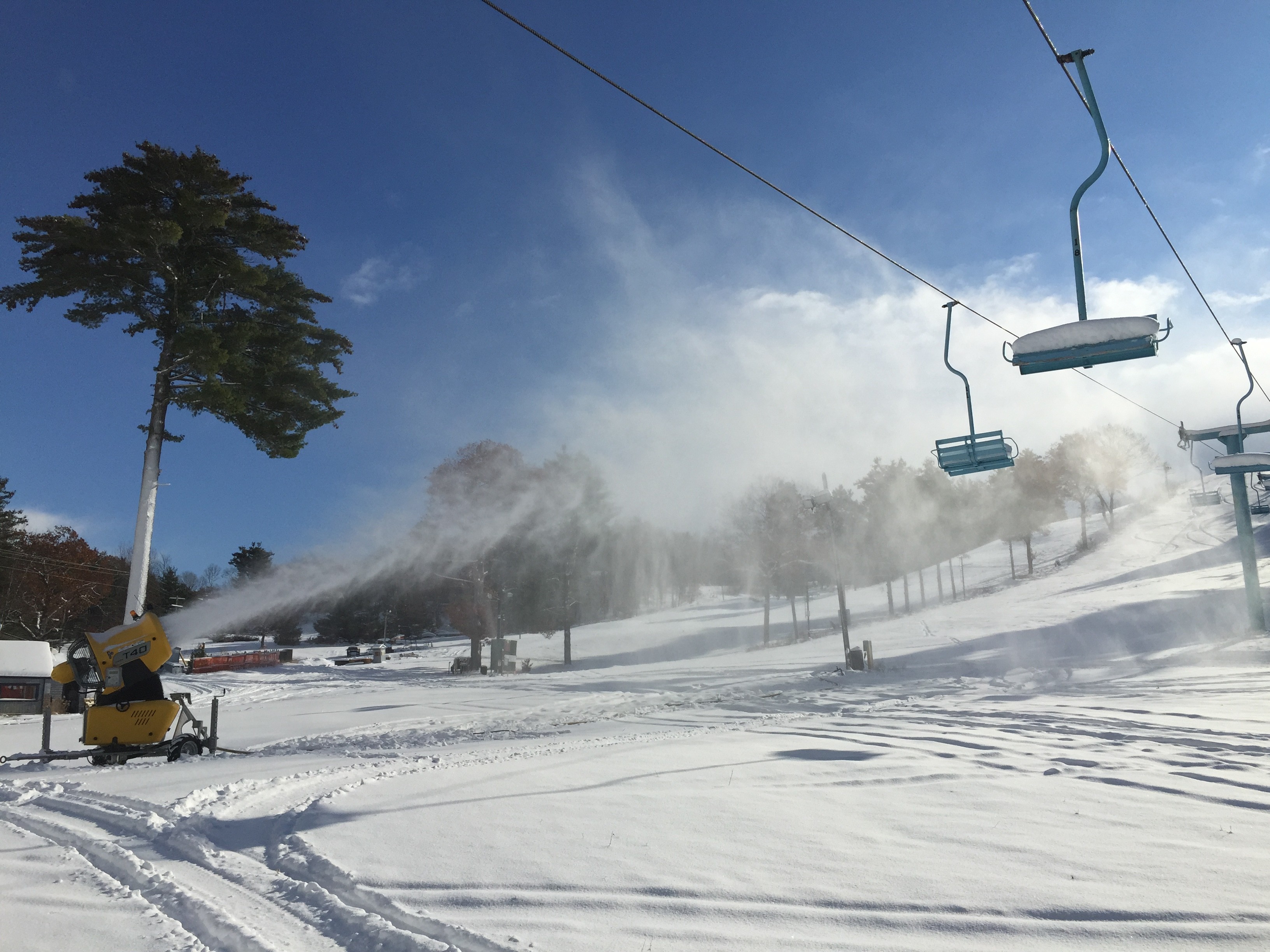 Winter scene at Mt Holiday, Michigan, featuring a ski lift operating in a ski resort amidst stunning winter scenery. A skier is seen enjoying the snowy landscape.
