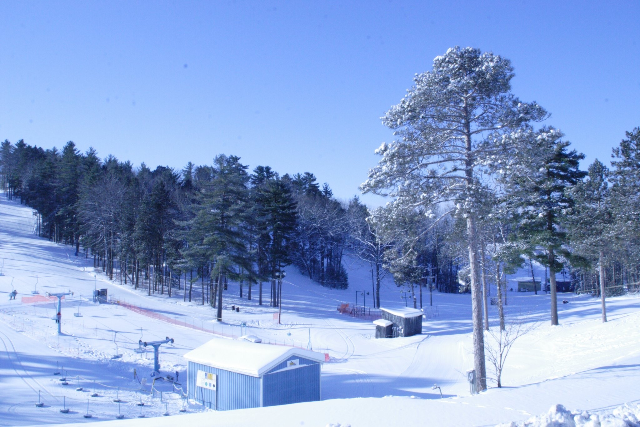 Winter scene at Mt Holiday, Michigan, with a bustling winter sports center nestled in the snow-covered landscape, offering skiing, and capturing stunning surrounding scenery.