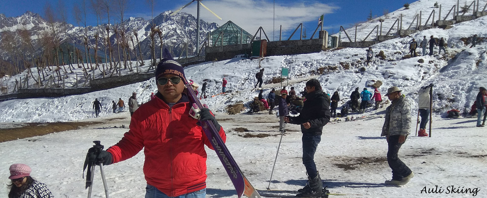 Auli in India - a man in a red jacket holding ski poles.