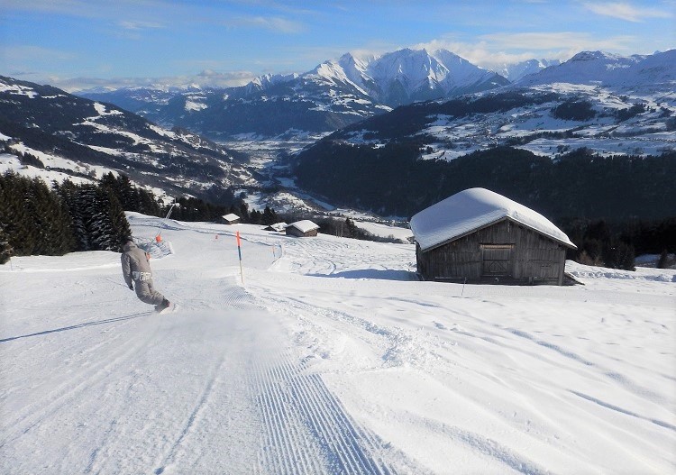 Winter sports enthusiasts enjoying the snowy slopes at Brigels Waltensburg Andiast, a ski resort in Eastern Switzerland, with a charming chalet and stunning winter scenery in the backdrop.