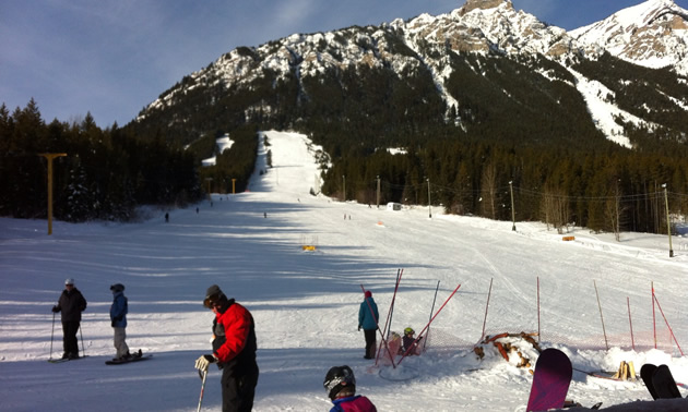 A skier enjoying a winter day at Wapiti Ski Hill in the Kootenay Rockies British Columbia Canada with a ski lift and mountain in the background.