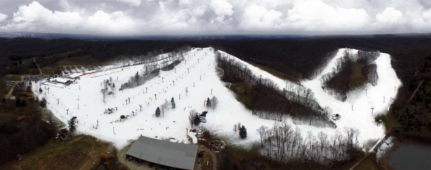 A bustling winter sports scene at Snow Creek in Missouri USA showcasing a ski resort with a ski lift and snow-covered slopes filled with enthusiasts engaged in various winter activities.