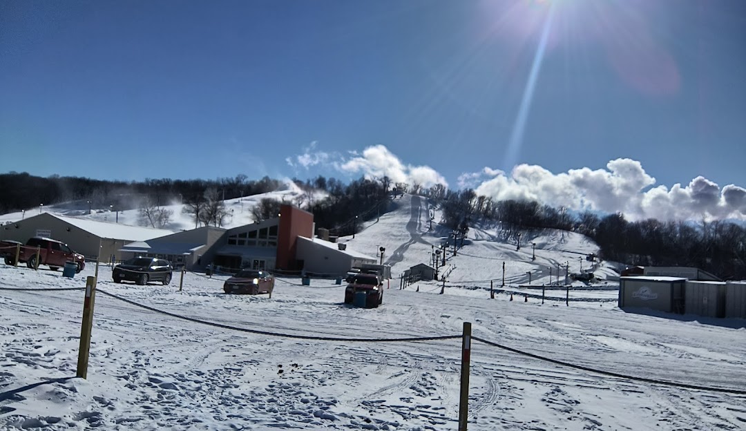 Winter sports enthusiasts enjoying a day at Snow Creek ski resort in Missouri, USA. A quaint chalet overlooks a stunning snow-covered landscape.