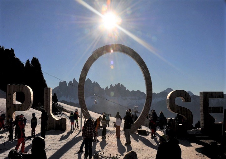 Winter sports enthusiasts enjoying a sunny day at the Plose - Brixen ski resort in South Tyrol, Italy. Wide pristine snow-covered scenery, with a chalet blending into the stunning landscape.
