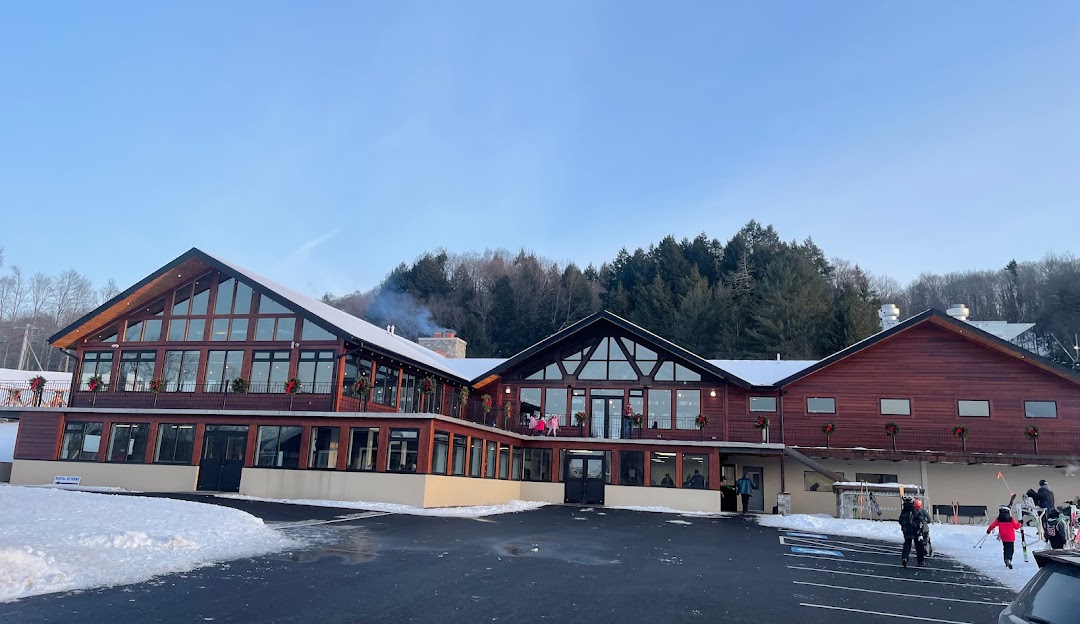 A view of Woods Valley winter sports centre in Central New York featuring a ski resort with a lodge and a cozy challet against a backdrop of snowy slopes bustling with winter sports activities.