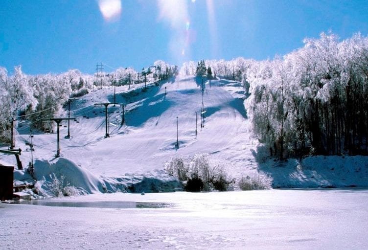 A picturesque view of Mount Peter ski resort in Hudson Valley New York showcasing winter sports scene with a ski lift and a charming chalet amidst the snow-filled panoramic beauty.