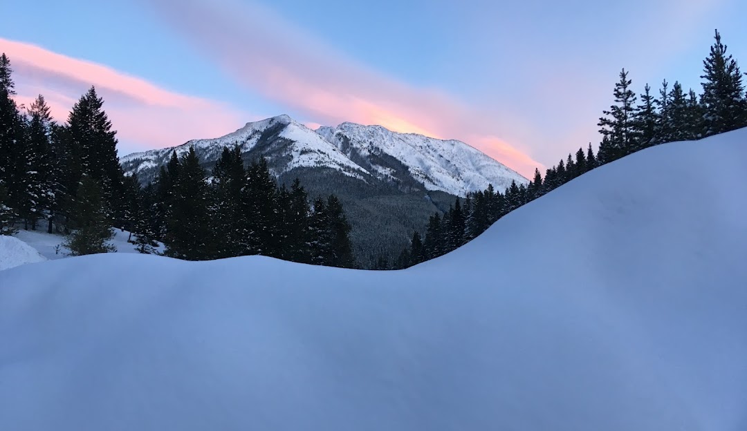 View of the majestic, snow-capped mountains in Pass Powderkeg, a ski resort in Southern Alberta, Canada. Winter sports enthusiasts can be seen enjoying the pristine winter scenery.