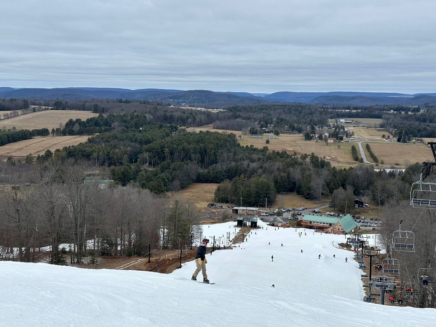 Winter scene at Sawmill Mountain Resort in Pennsylvania, highlighting snow-covered slopes, a ski lift, and a skier enjoying the terrain.