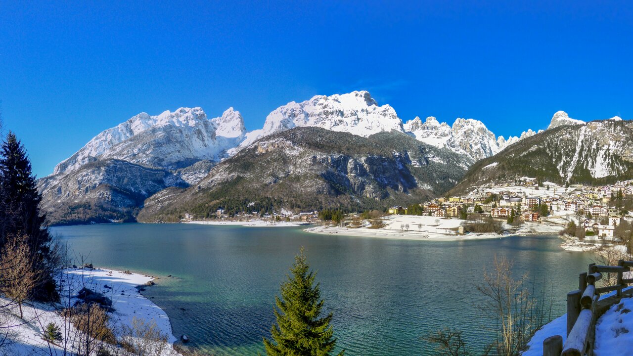Pradel – Molveno in Italy - a lake surrounded by snow and mountains in the background.