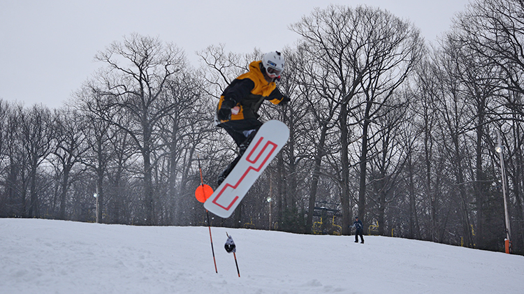 A snowboarder navigating the snowy slopes at Victor Constant Ski Area, West Point in Hudson Valley, New York. The rider's swift movements leave a fresh trail in the crisp, untouched snow.