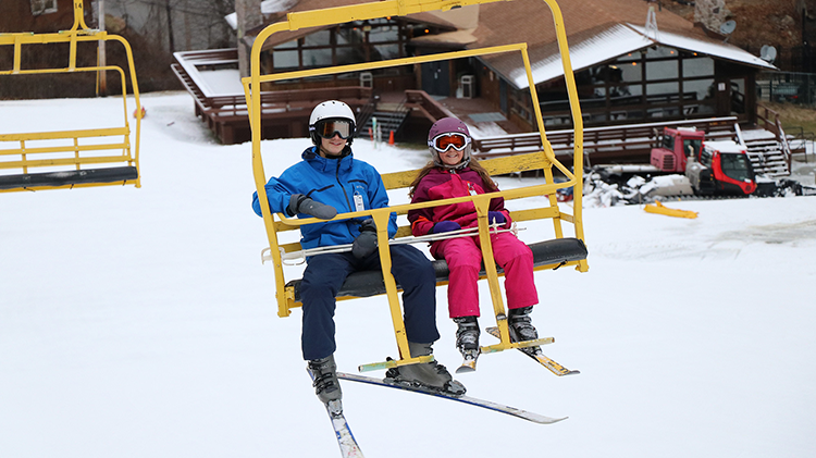 Ski lift ascending hill at Victor Constant Ski Area in West Point, New York, with skiers navigating snow-covered slopes amidst a picturesque winter landscape.