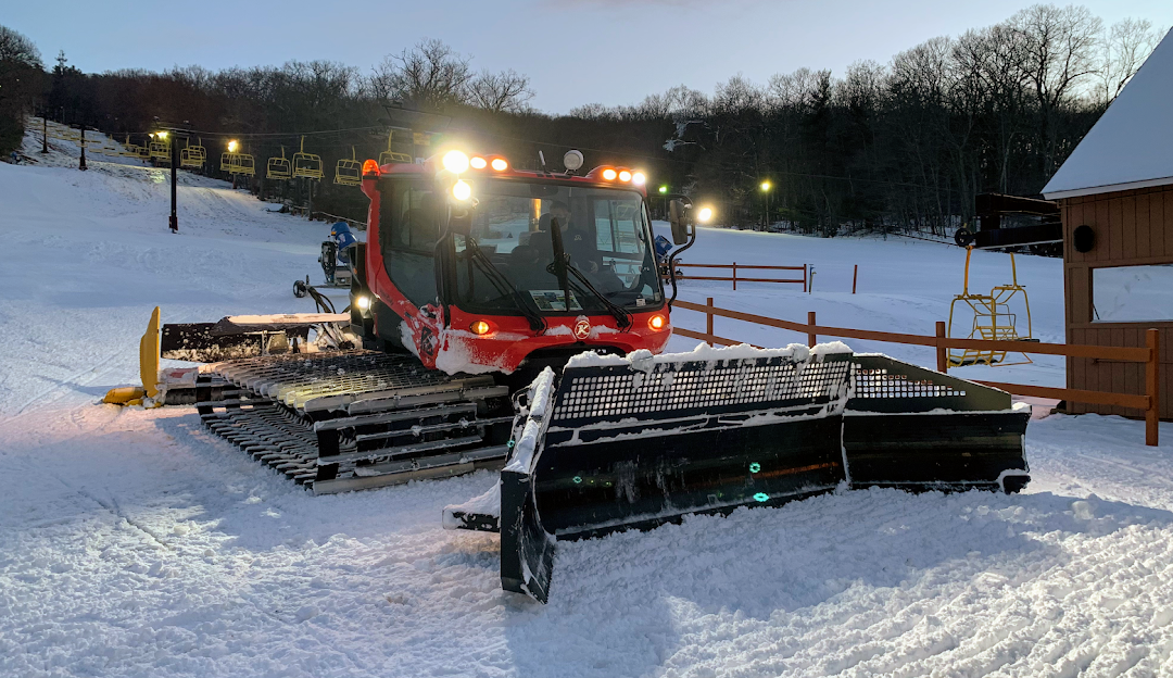Winter scene at Victor Constant – West Point in Hudson Valley, showcasing a ski lift and active snowmobile amid a bustling ski resort with a chalet in the background.