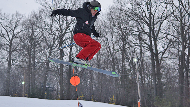 A skier and snowboarder navigating through a winter sports scene at Victor Constant – West Point in Hudson Valley New York with a distant ski lift barely visible.