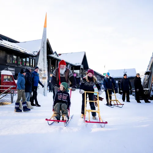 Winter sports scene at Geilo, Hallingdal, Norway featuring a skier sliding down a smooth snowy slope at a popular ski resort, with a snowmobile parked nearby.