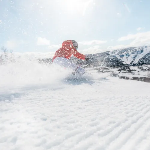A skier in action at Geilo in Hallingdal, Buskerud, Norway. The winter sports scene complete with a snowmobile brings life to the scenic ski resort.