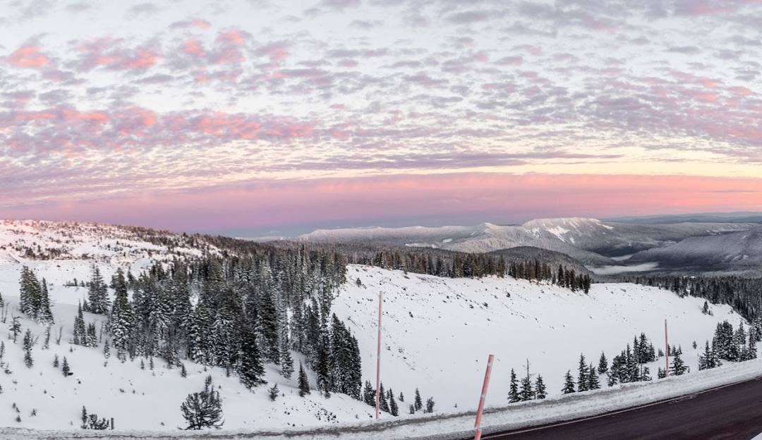 View of Timberline Summit Pass in Oregon, USA during winter, featuring a bustling ski resort with a busy ski lift. The landscape is a breathtaking winter scene filled with winter sports enthusiasts.