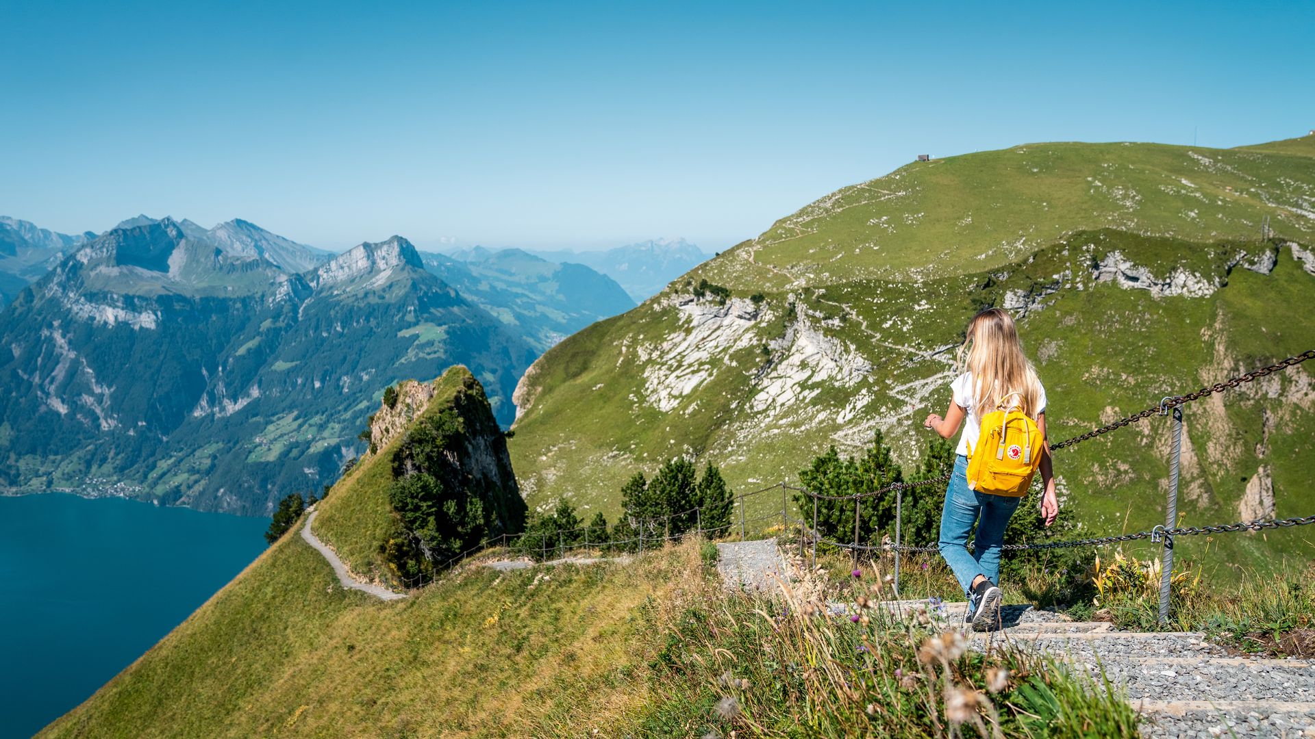 A rustic chalet nestled on the upper slopes of a mountain in Stoos, Central Switzerland, bathed in sunlight. A mountain bike at the foreground hints at outdoor pursuits.