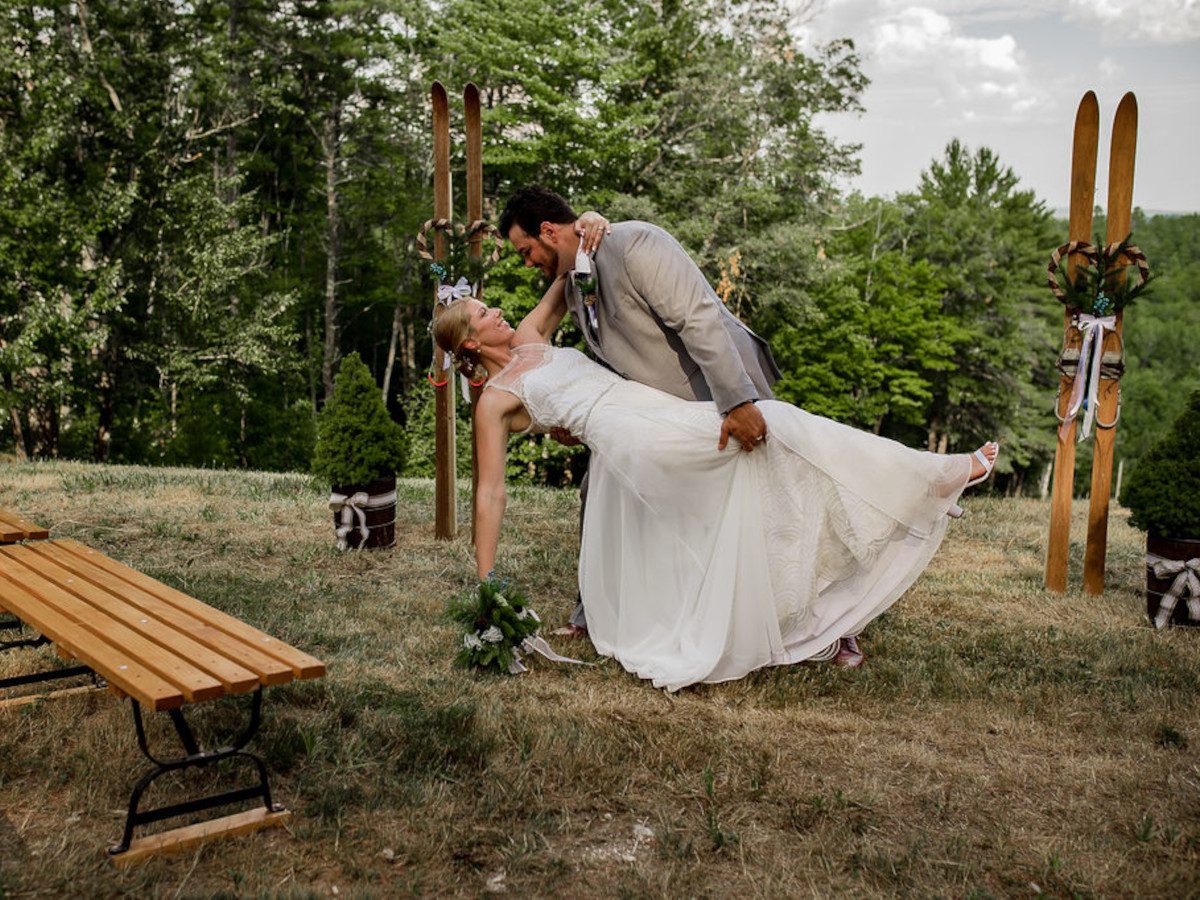 Lost Valley in USA - a bride and groom kissing in front of a wooden bench.