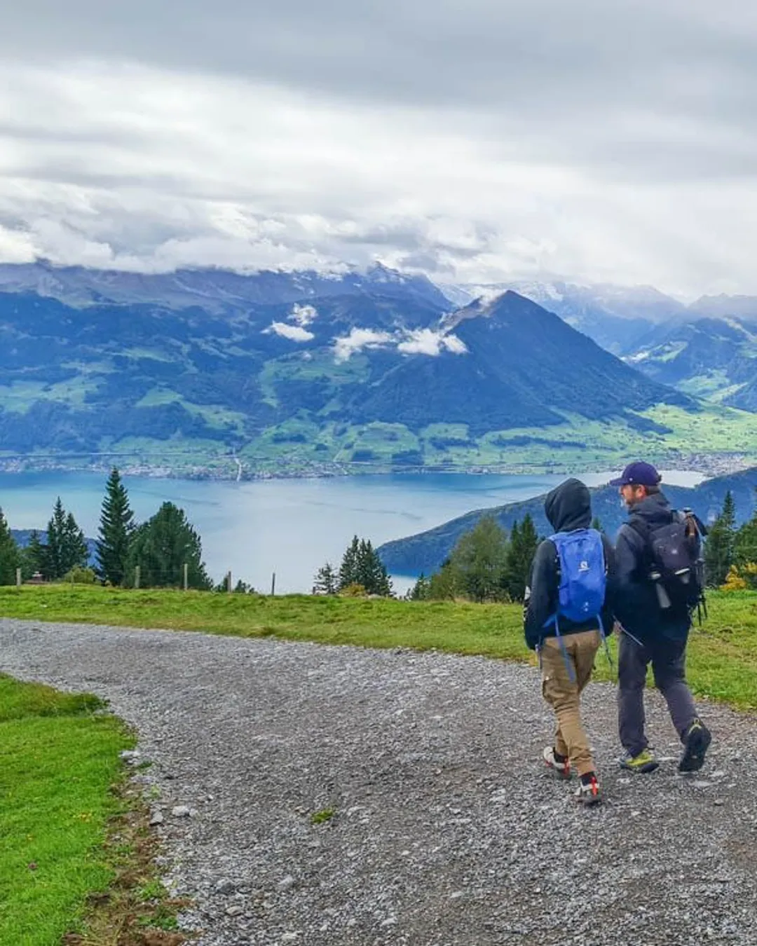 Rigi – Scheidegg | Burggeist in Switzerland - two people walking on a path with mountains in the background.