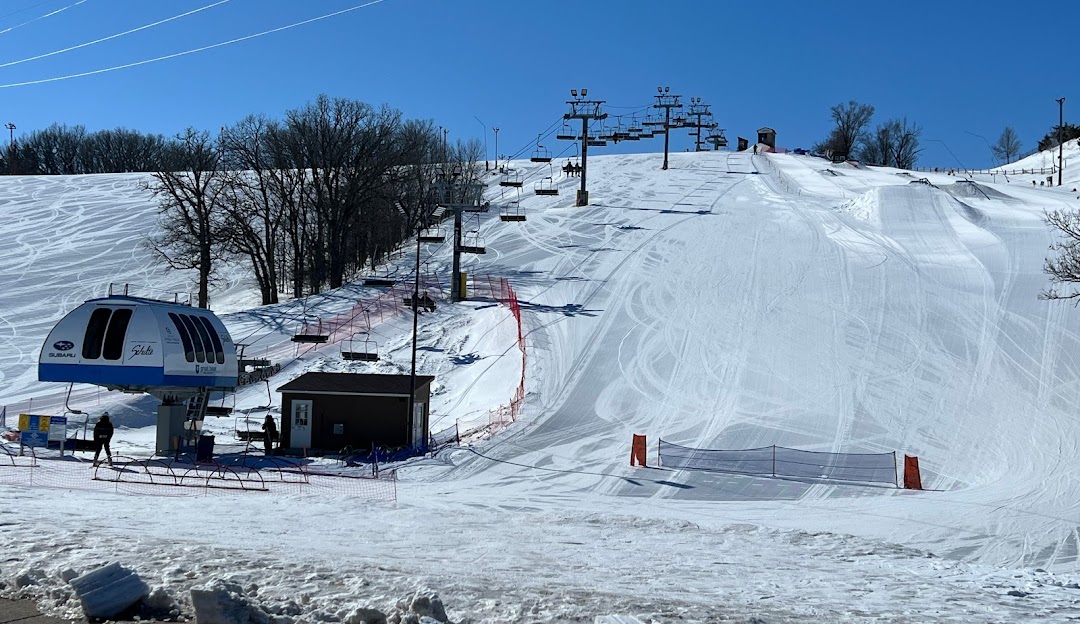 Skier glides down snowy slopes at Great Bear Ski Valley, South Dakota. A ski lift, a crucial part of the winter sports scene, is visible in the background of this lively ski resort.