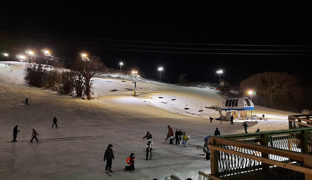 View of Great Bear Ski Valley in South Dakota, featuring a bustling ski resort, ski lift, and winter sports activities amidst a stunning winter landscape.