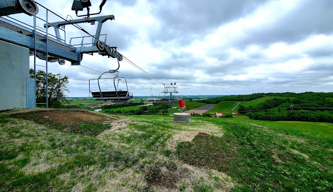 View of the Great Bear Ski Valley in South Dakota,highlighting a prominent ski lift and a distant chalet, with a hint of a ski resort in the serene winter backdrop.