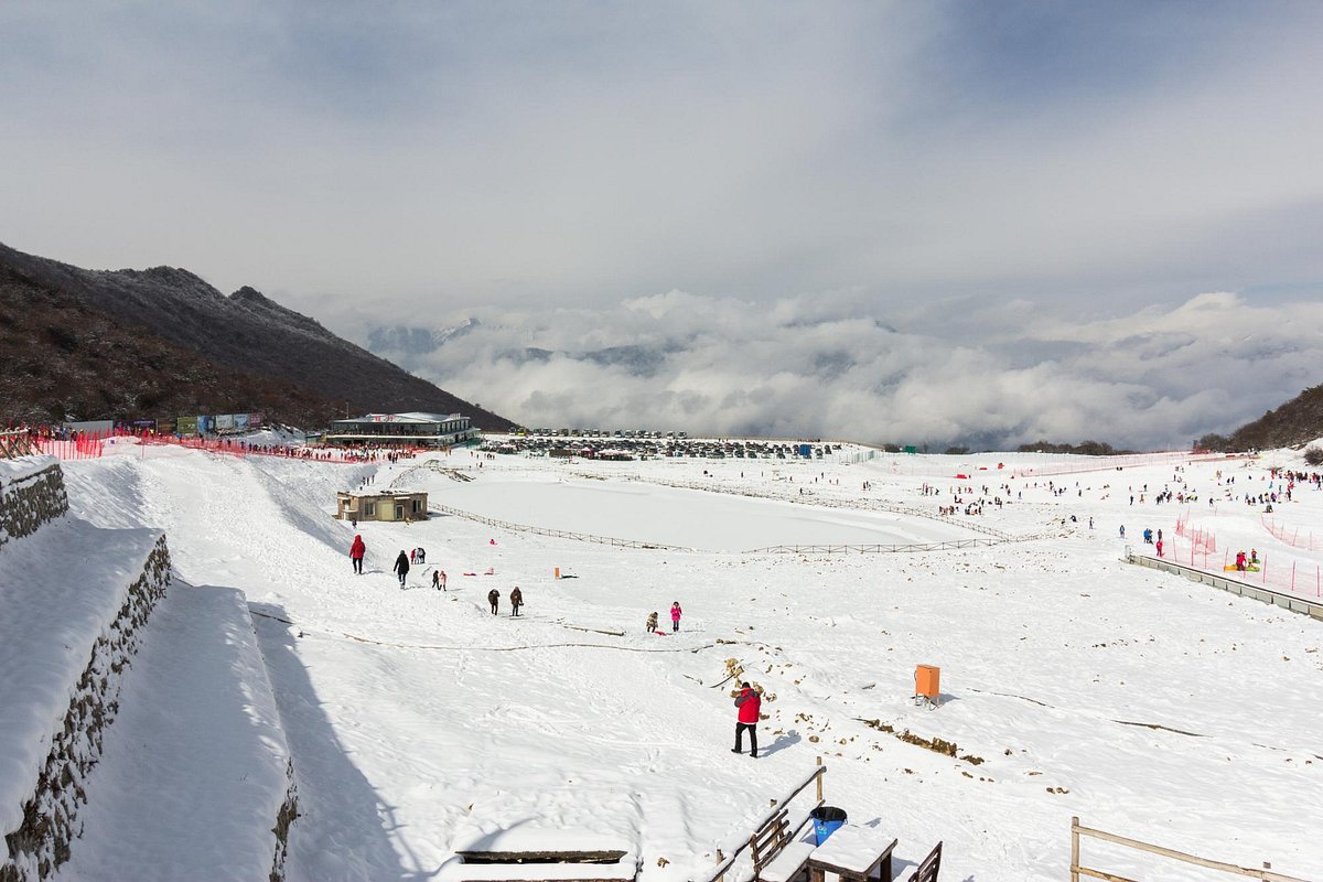 Jiudingshan Taiziling in China - a group of people skiing down a snow covered slope.