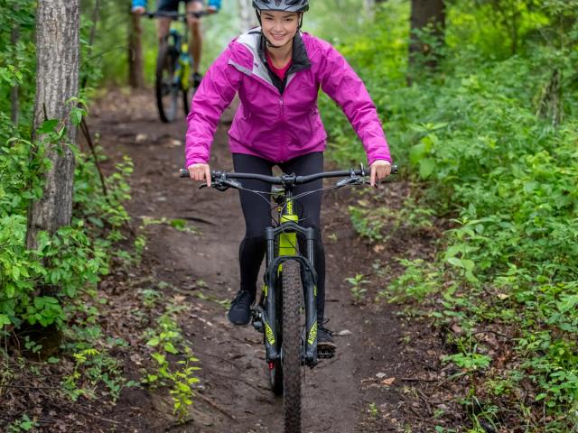 A mountain bike is prominently featured in the foreground of an image from Nitehawk Northern Alberta with a remote chalet faintly visible in the background.