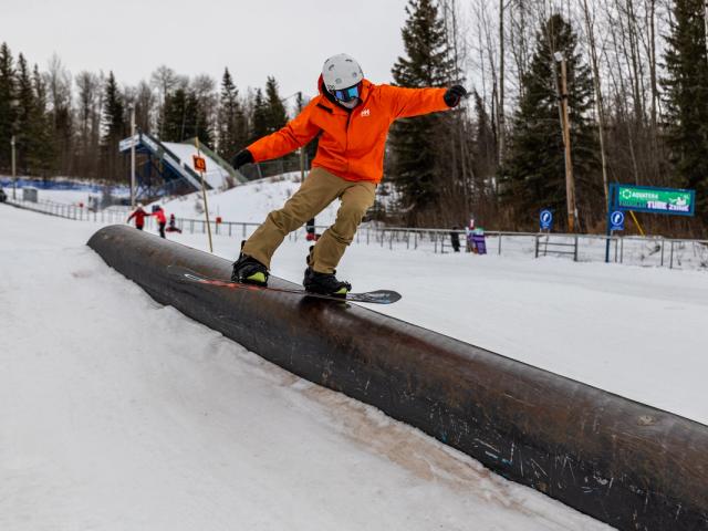 A snowboarder skillfully carving down the snowy slopes at Nitehawk Northern Alberta Canada surrounded by the serenity of the alpine environment.