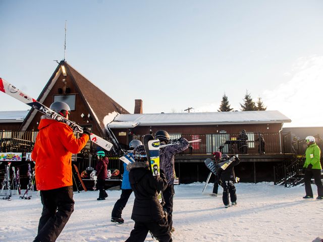 A vibrant winter sports scene at Nitehawk Northern Alberta Canada showcasing a skier gliding down a snow-covered slope with ski lifts and resort facilities in the background.