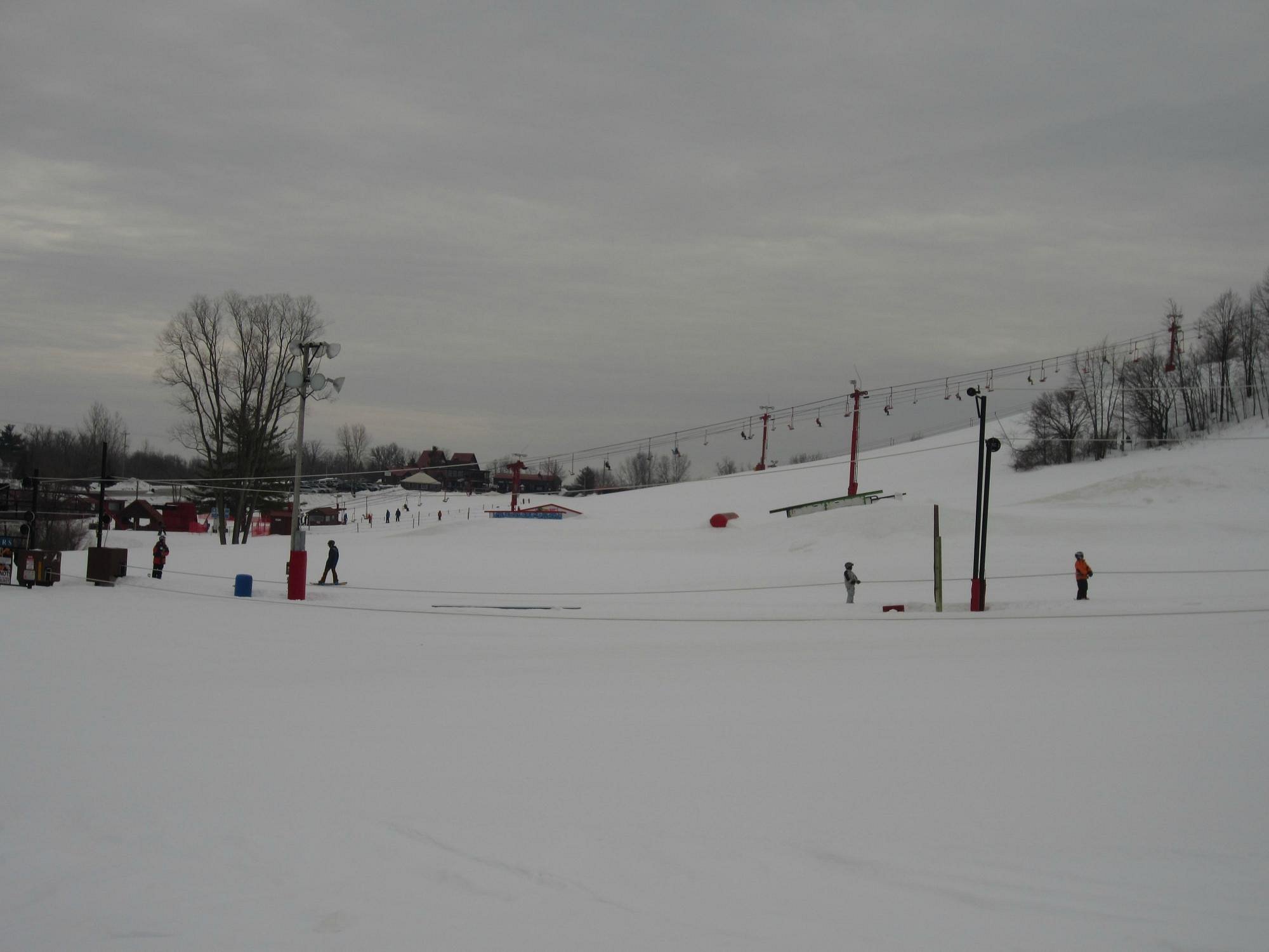 Winter sports enthusiasts enjoying a day at Sunburst, Wisconsin, with a scenic view of a ski resort, winter sports center, chalet, and ski lift amidst a snowy landscape.