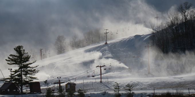 View of the popular Sunburst ski resort in Wisconsin, showcasing its bustling winter sports scene. A ski lift can be seen leading up to the snow-covered slopes of the mountain.
