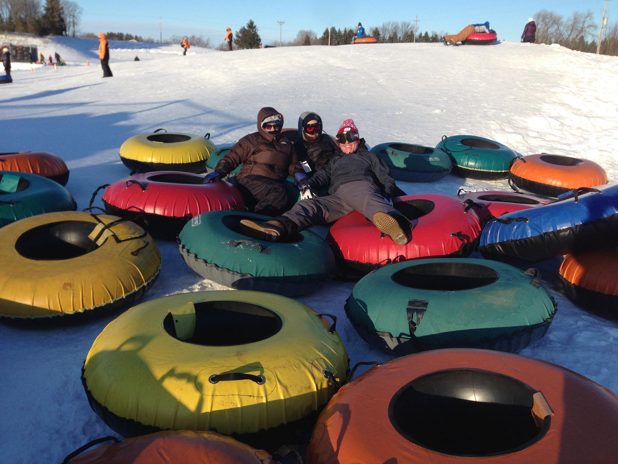 Winter sports scene at Sunburst, Wisconsin, showcasing a bustling ski resort, complete with a chalet and a snowmobile parked nearby.
