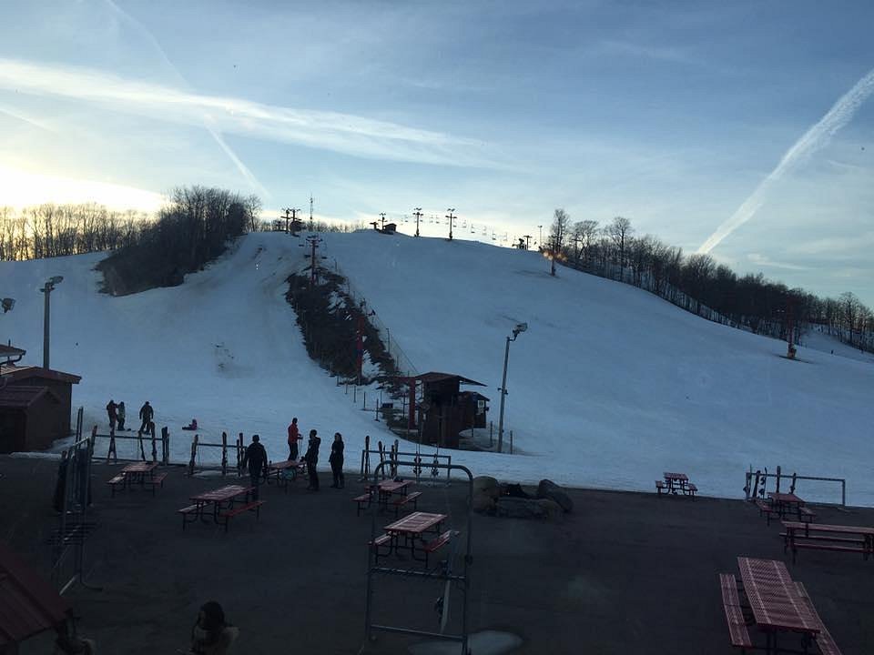 View of Sunburst ski resort in Wisconsin USA featuring ski slopes bustling with winter sports enthusiasts. A ski lift is visible against the backdrop of a mountain.