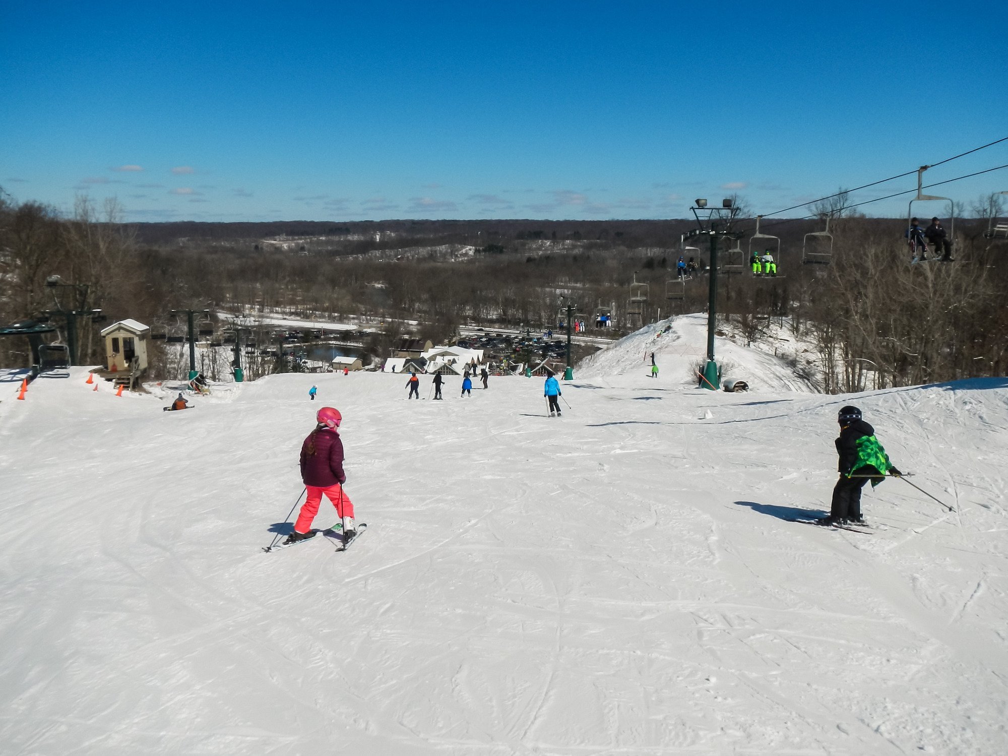 Winter sports enthusiasts enjoy a day of skiing at Boston Mills resort in Peninsula, Ohio, with individuals zooming downhill and others taking a ski lift for another run.