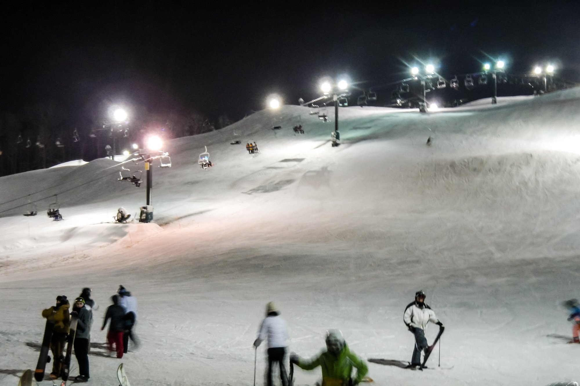 A lively winter sports scene at Boston Mills in Peninsula Ohio featuring skiers enjoying slopes at a popular ski resort aided by a ski lift.