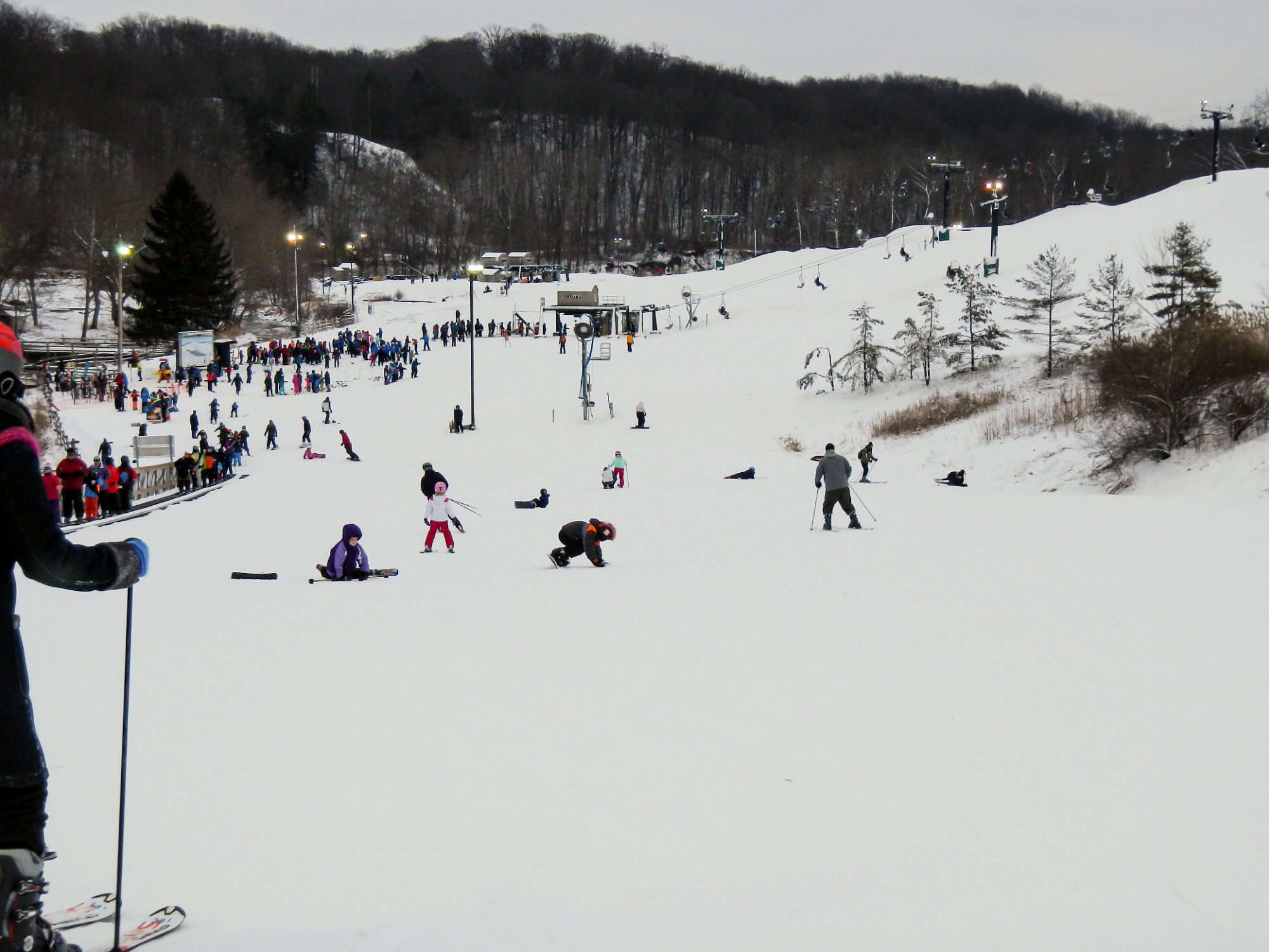 Winter sports enthusiasts flock to Boston Mills in Peninsula, Ohio, a ski resort bustling with activity. A skier takes a ski lift ride up the snowy slope, ready to dive into another exhilarating downhill adventure.