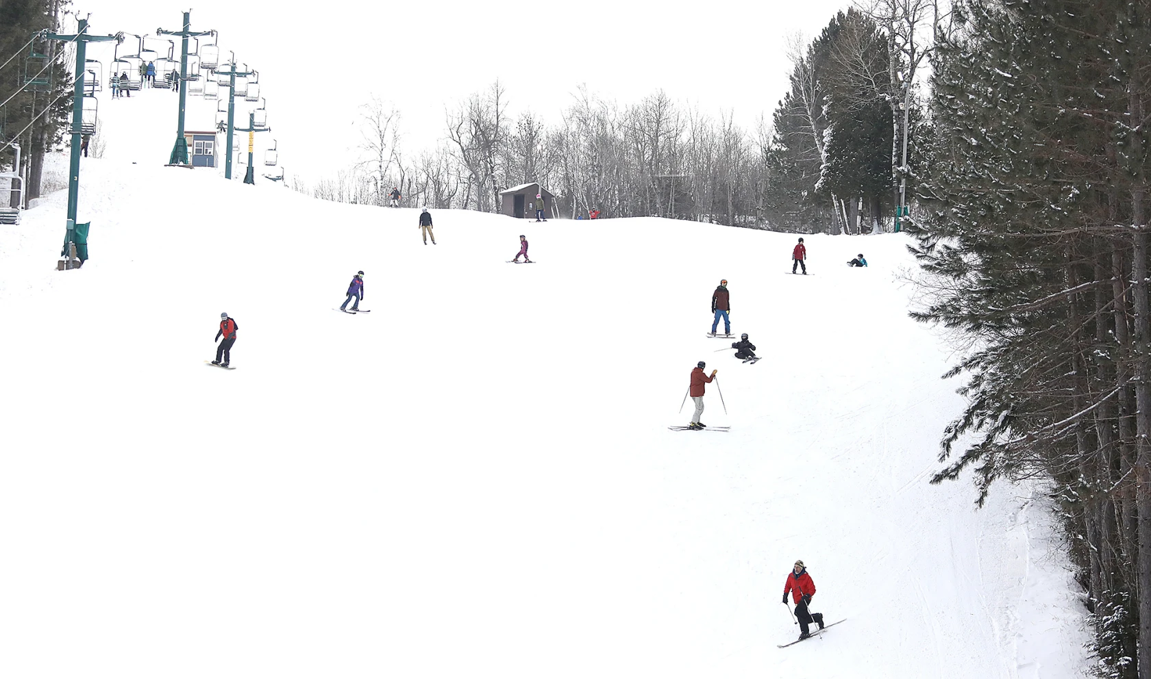 Winter scene at Chester Bowl, Minnesota, showcasing a busy skiing day at the resort. The challet and ski lift add to the charming ambiance of this local winter sports center.