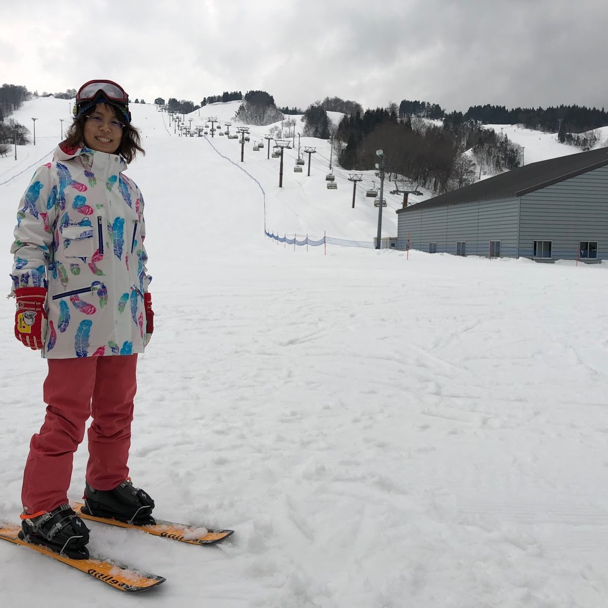 Taranokidai in Japan - a little girl standing on a snowboard in the snow.