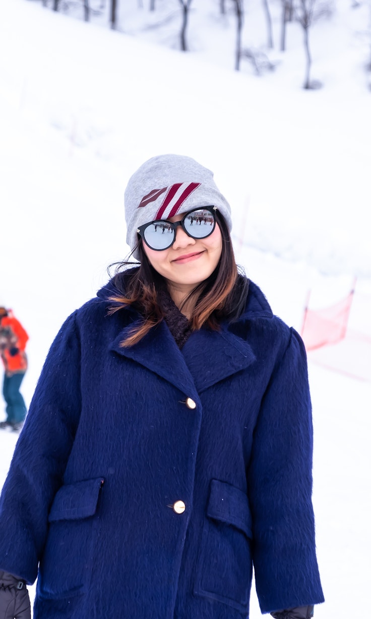 Koide in Japan - a woman standing in the snow wearing a blue coat.
