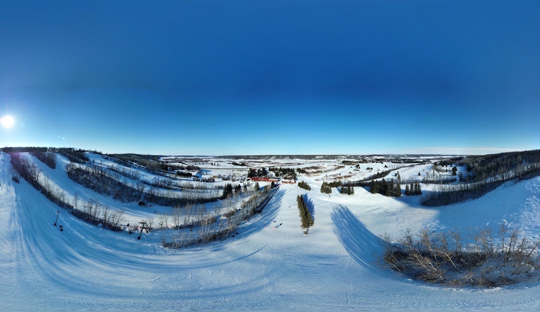 Winter scene at Holiday Mountain, Manitoba, Canada, showcasing a vibrant winter sports scene. A charming chalet situated amongst stunning winter scenery, highlighted by a sports centre in the background.