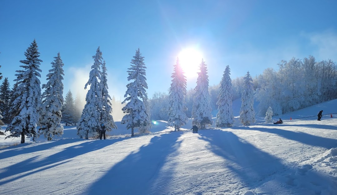 A breathtaking winter panorama at Holiday Mountain in Manitoba, Canada, bustling with winter sports activity. The scenic beauty of the snow-covered terrain shines brilliantly under the afternoon sun.