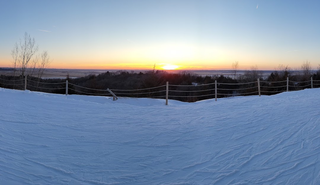 A charming chalet at Mt Crescent Iowa USA set amidst a stunning winter landscape. The scene showcases a bustling winter sports center with people enjoying the snowy terrain. This image encapsulates the thrilling beauty of winter sports.