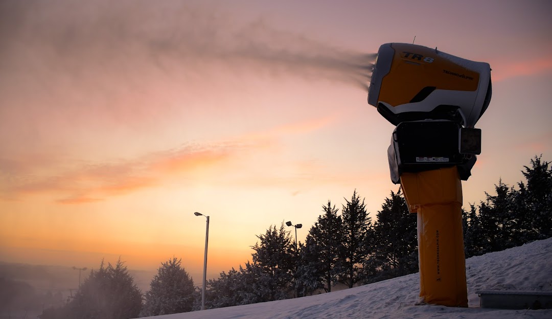 Winter sports scene at Mt Crescent, Iowa, USA with a snowmobile parked in front of a chalet against a stunning backdrop of snow-covered landscape.