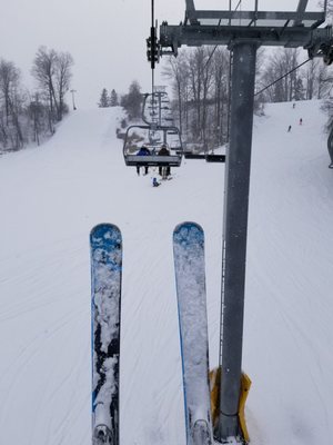 Winter scene at Uplands Ski Centre in Southern Ontario, Canada, featuring a ski lift, a skier gliding down the slopes, and surroundings befitting a ski resort.